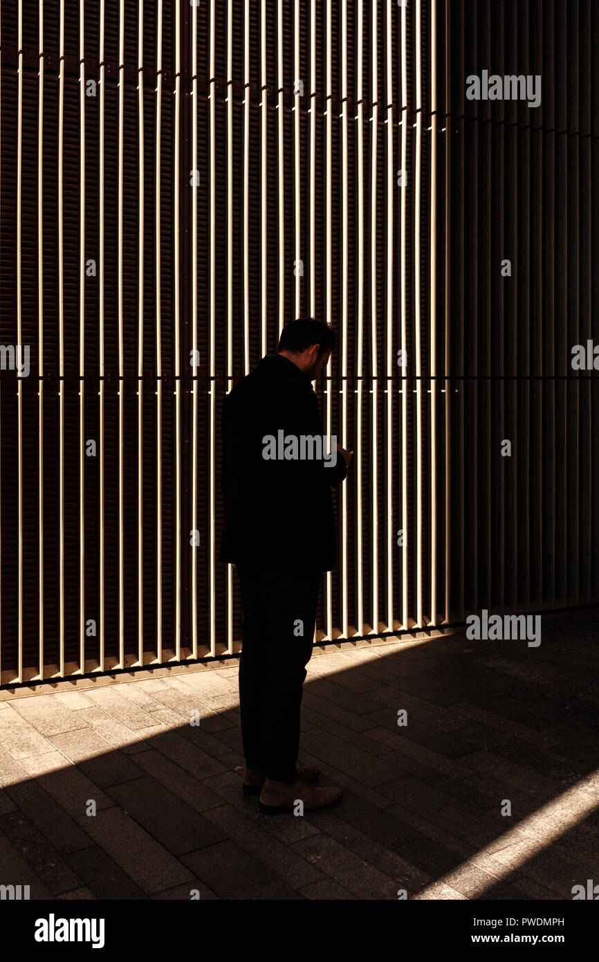 UK, London, Mittagspause. Mann Rauchen außerhalb des Büros, auf seinem Telefon Stockfoto