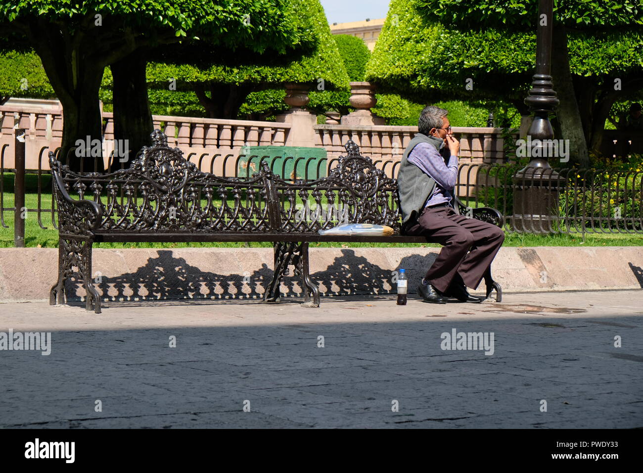 Mexikanischer Mann mittleren Alters, der auf einer Parkbank auf dem hauptplatz in Leon, Guanajuato, Mexiko sitzt; älterer Mann, 50s oder 60s Jahre alt. Stockfoto