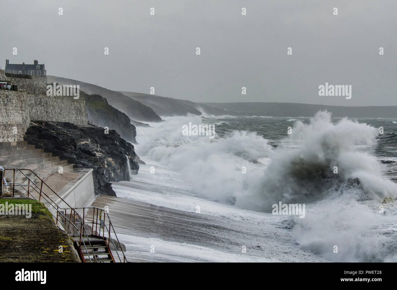 Porthleven Hafen, Porthleven Clock Tower Cornwall und Klippen mit großen Absturz Wellen während Winterstürmen Stockfoto