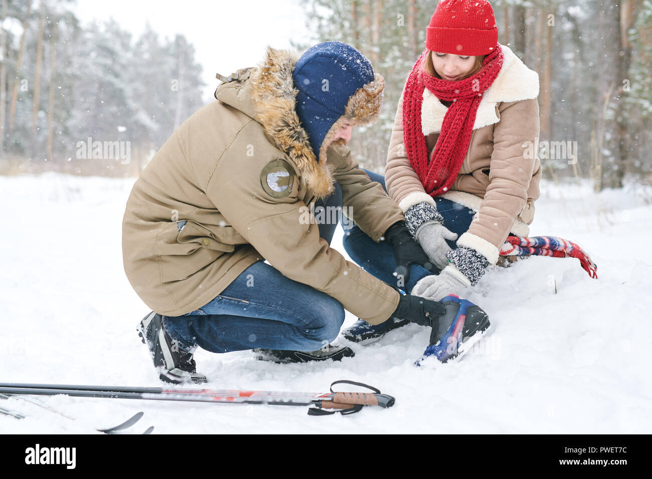 In voller Länge Porträt der Pflege junger Mann helfen verletzten Freundin während Ski laufen Im Winter Wald Stockfoto