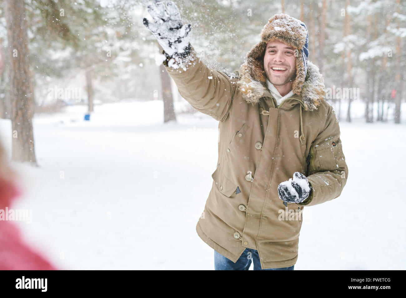Taille bis Portrait von gutaussehenden jungen Mann genießen Schneeballschlacht mit Freunden im schönen Winter Forest, kopieren Raum Stockfoto