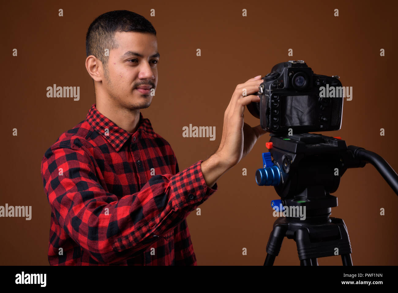 Junge multi-ethnischen asiatischer Mann gegen braunen Hintergrund Stockfoto