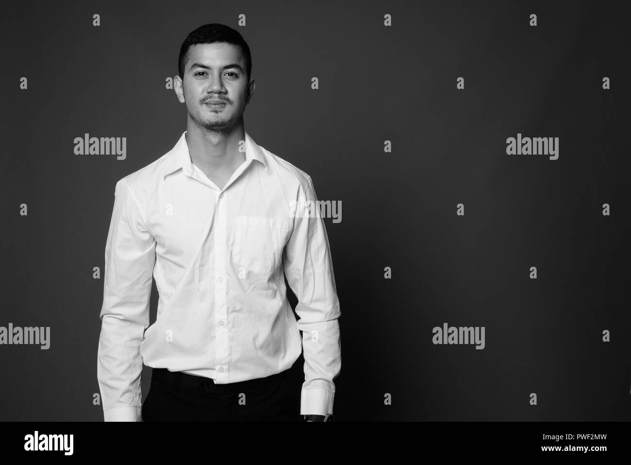 Junge multi-ethnischen asiatische Geschäftsmann gegen grauen Hintergrund in Stockfoto