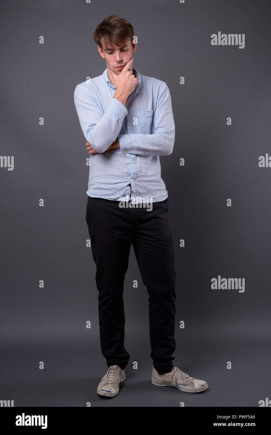 Studio shot Junger stattlicher Mann gegen grauer Hintergrund Stockfoto