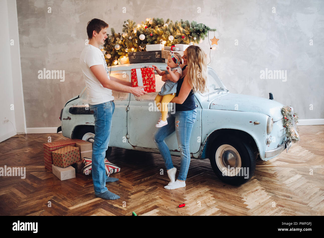 Blick auf schöne Daddy, Weihnachtsgeschenk, Big Red Box, für blonde Mutter und kleinen niedlichen Tochter. Familie Ausgabe Zeit zusammen im Haus eingerichtet w Stockfoto