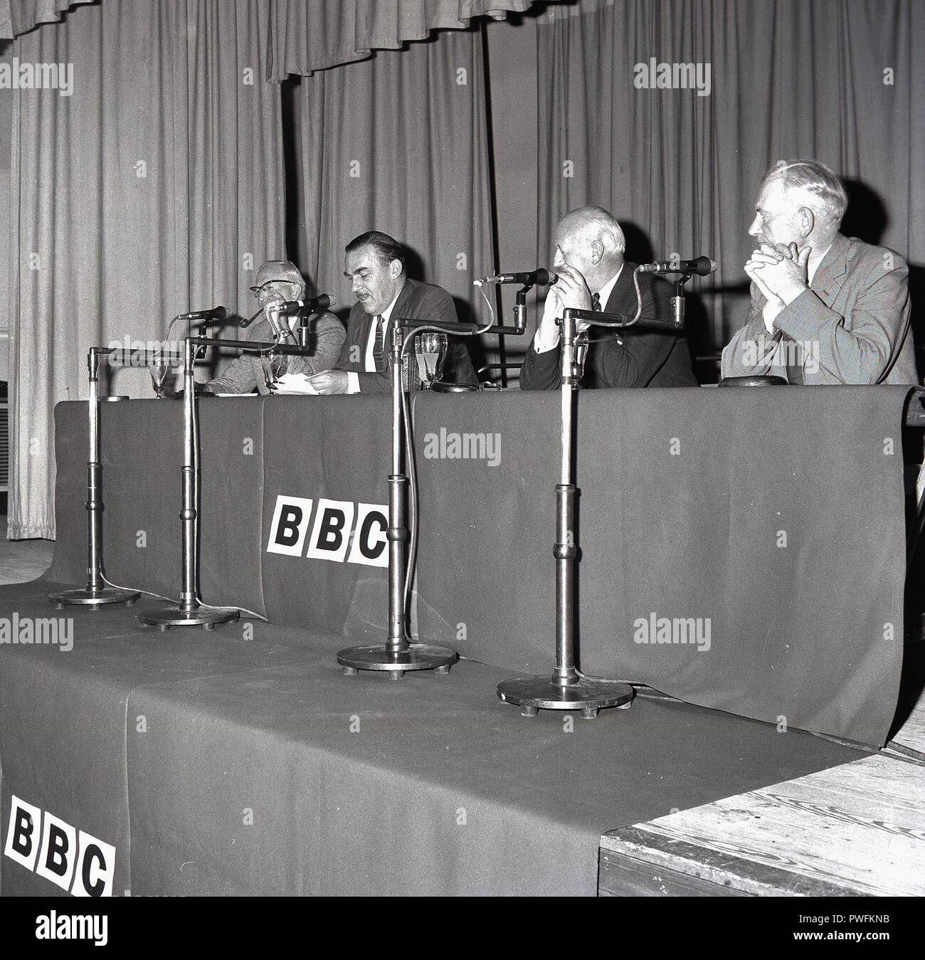 1967, ältere Mitglieder des Vorstands der BBC, die British Broadcasting Corporation, sitzen auf einer Plattform mit Mikrofonen für eine Präsentation und öffentliche Treffen, Bucks, England, UK. Stockfoto