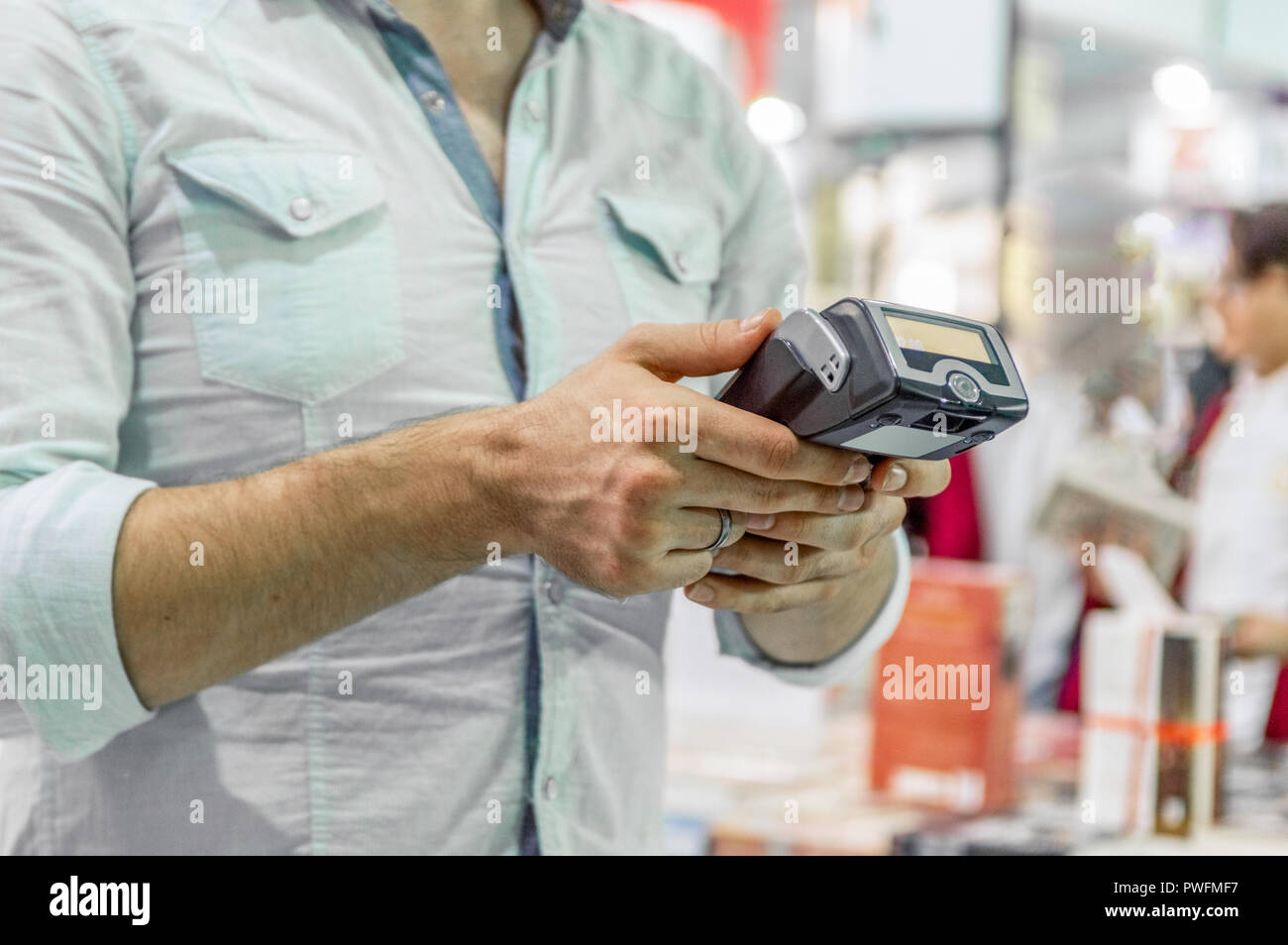 Kaukasische Verkäufer Mann hält Karte Maschine oder POS-Terminal in seinen Händen Stockfoto