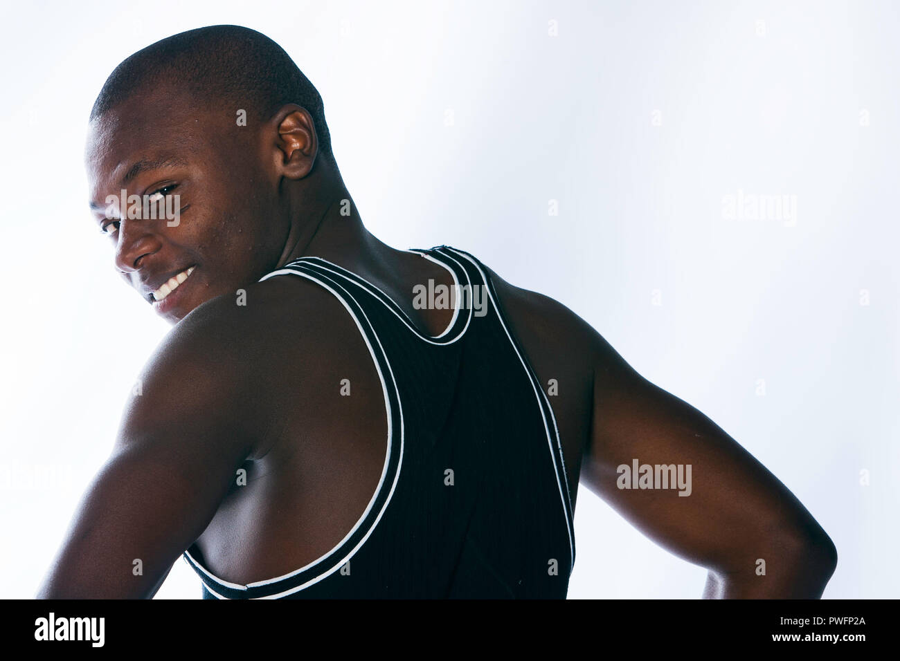 Anmutige junge afrikanische Mann trägt einen Muskel Hemd nach hinten, lächelnd. Stockfoto