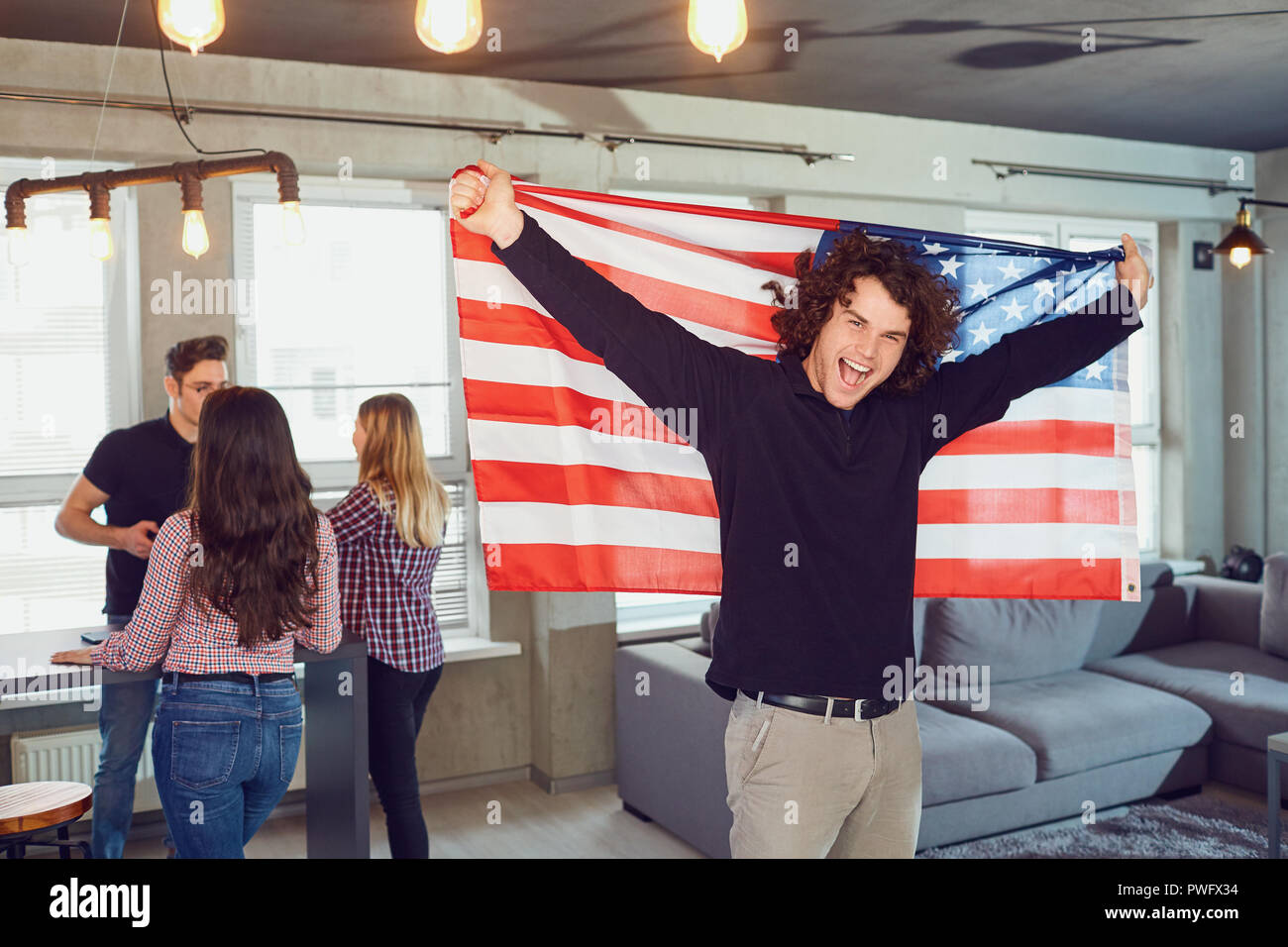 Kerl mit einem wunderschönen Lächeln mit der Flagge von Amerika im Innenbereich. Tag der Unabhängigkeit der USA. Stockfoto Kerl mit einem wunderschönen Lächeln mit der Flagge von Amerika im Innenbereich. Tag der Unabhängigkeit der USA. Stockfoto