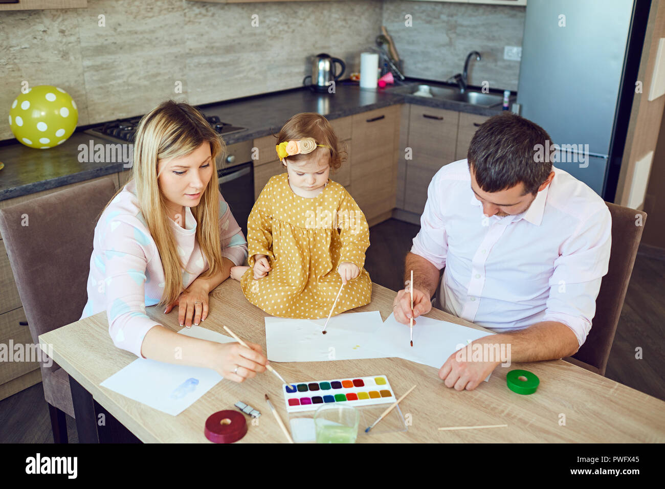 Mutter, Vater und Kind zeichnen zusammen am Tisch. Entwicklung der Kinder. Stockfoto