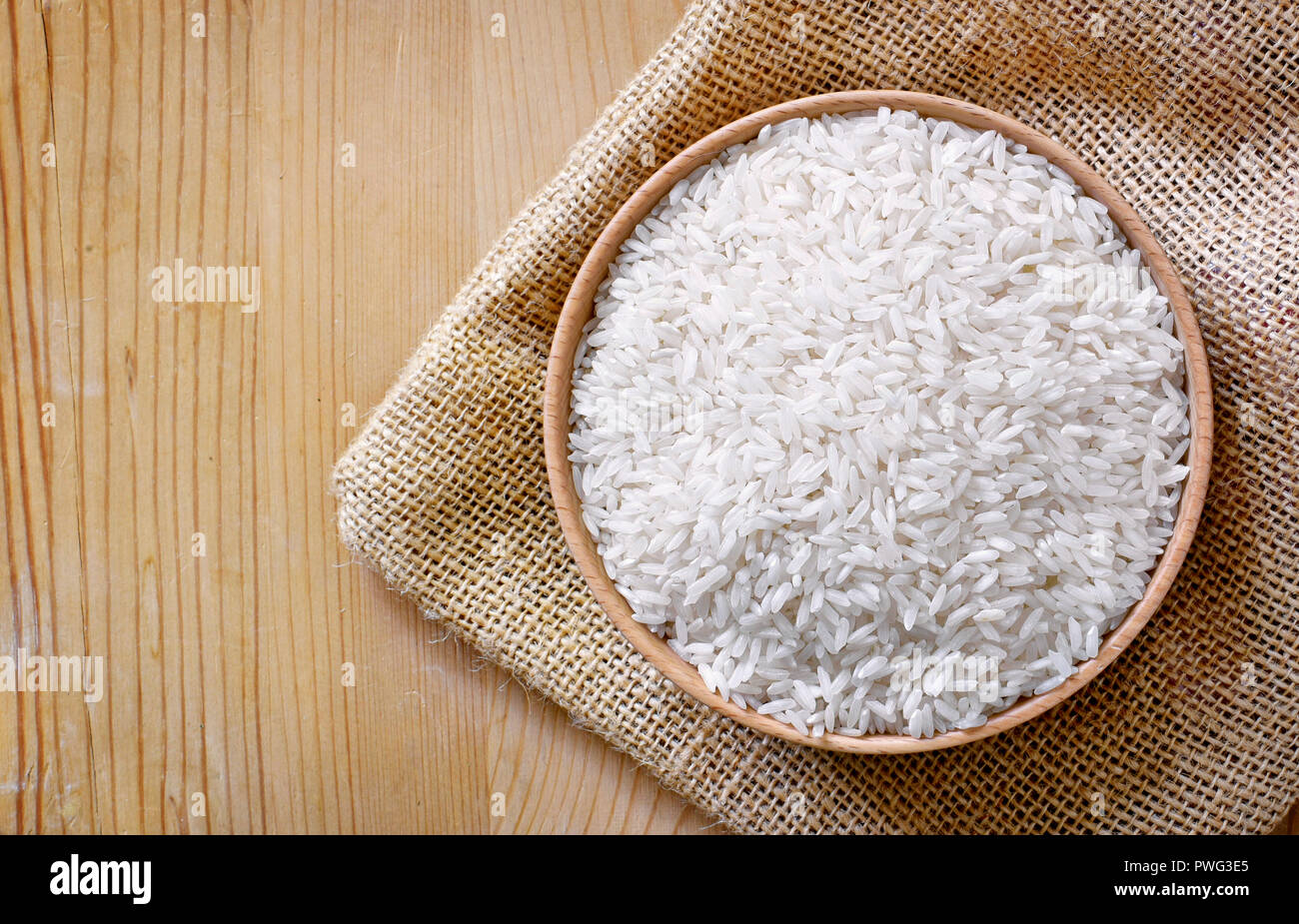Raw, parboiled Reis in eine hölzerne Schüssel. Reisgericht auf einen hölzernen Tisch, Diät oder gesunde Ernährung Szene. Stockfoto