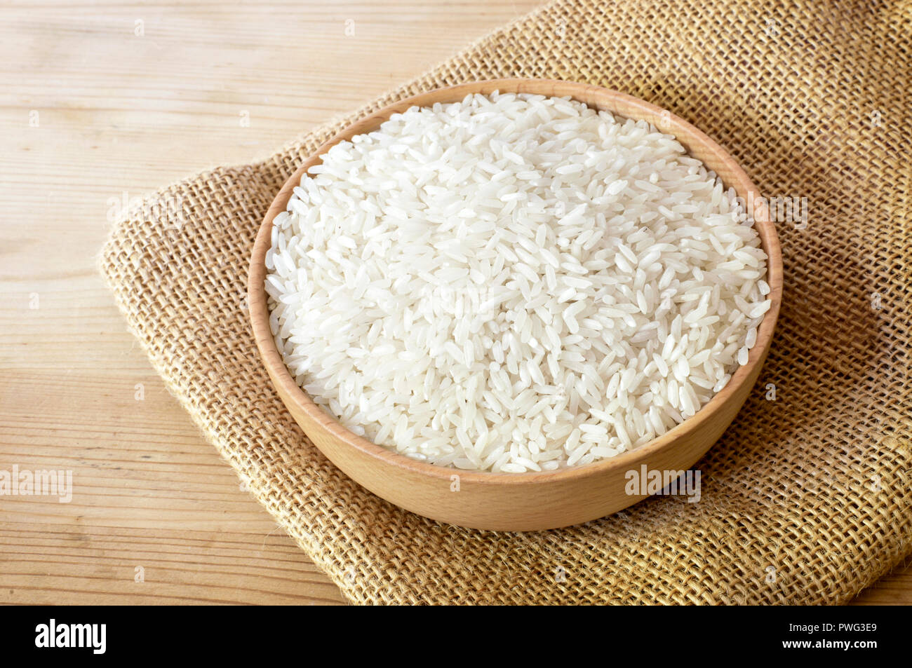 Raw, parboiled Reis in eine hölzerne Schüssel. Reisgericht auf einen hölzernen Tisch, Diät oder gesunde Ernährung Szene. Stockfoto