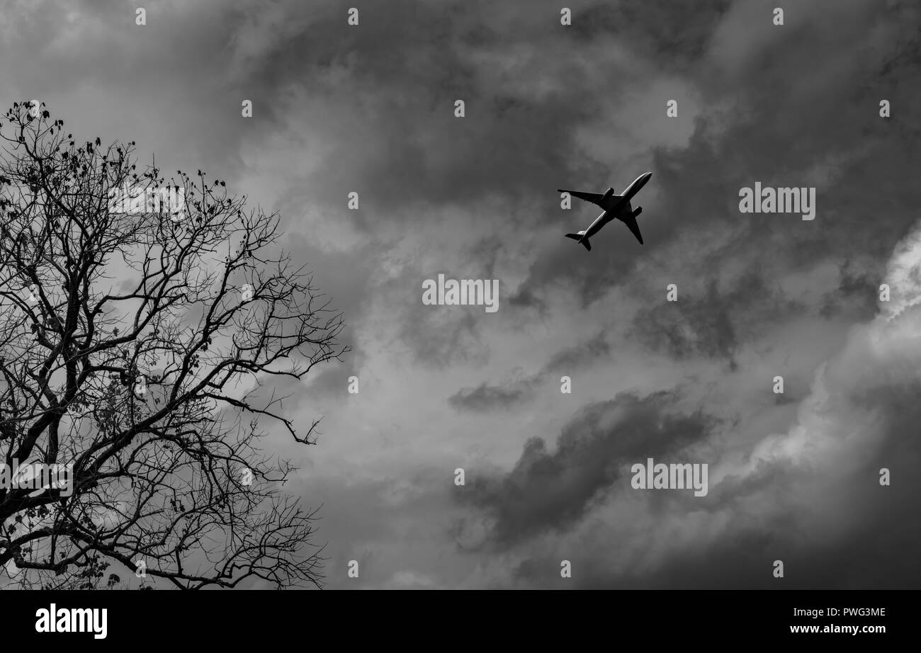 Silhouette Commercial Airplane auf grauem Himmel und Wolken mit dem Tod. Fehlgeschlagen. Hoffnungslosigkeit und Verzweiflung Konzept. Moody Himmel und Verkehrsmittel Flugzeug. S Stockfoto