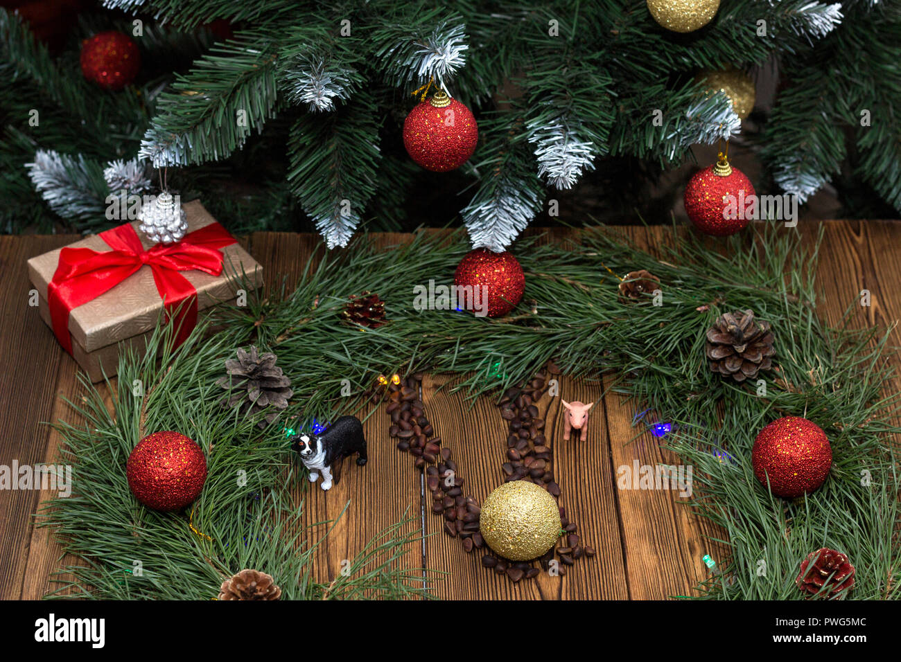 Neues Jahr aus Tannenzweigen und neues Jahr Spielzeug, Box mit neuen Jahr Geschenk, Spielzeug schweine und Hunde, auf dem Hintergrund des neuen Jahres Baum, Holz- hinterg Stockfoto