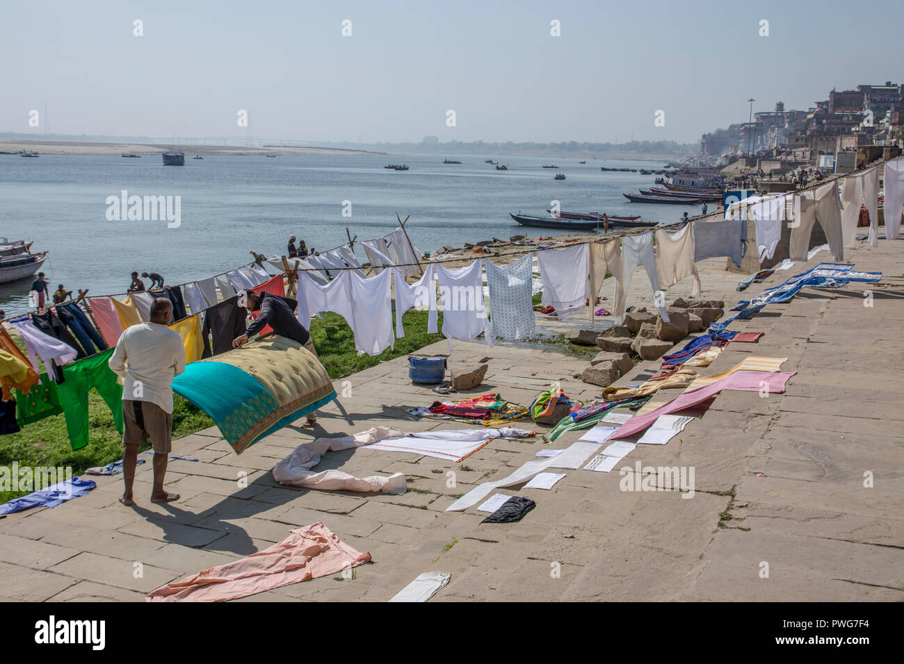 Wäscheservice Tag auf dem Ganges, Varanasi, Uttar Pradesh, Indien. Kleidung und Bettwäsche sind im Fluss und verteilen sich auf die Bank des Flusses zu trocknen Waschen Stockfoto