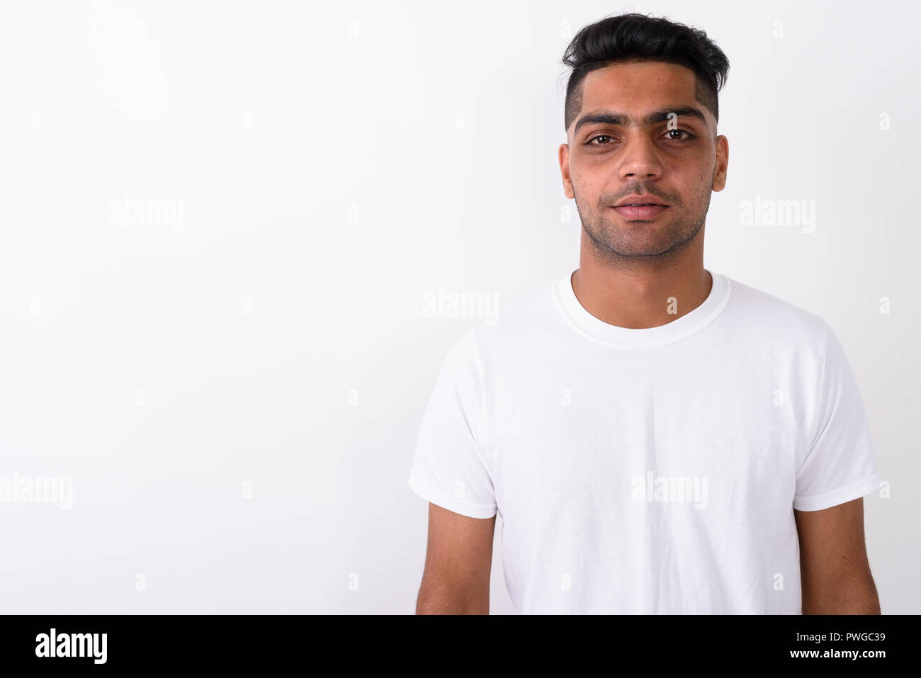 Junge indische Mann mit weißem Hemd gegen den weißen Hintergrund Stockfoto