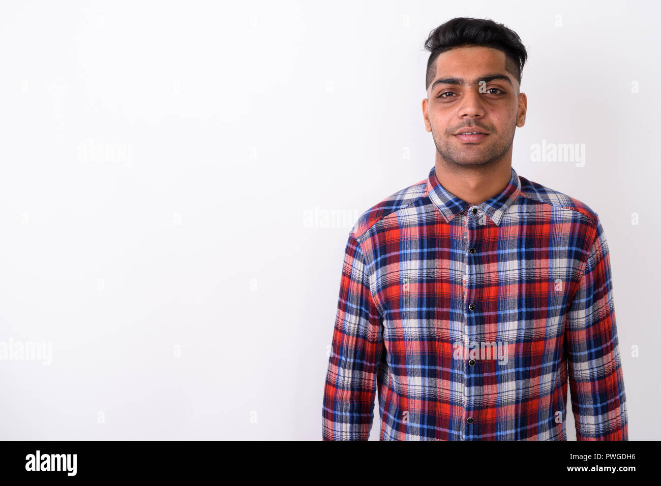 Junge indische Mann mit kariertem Hemd gegen Weiße backgroun Stockfoto