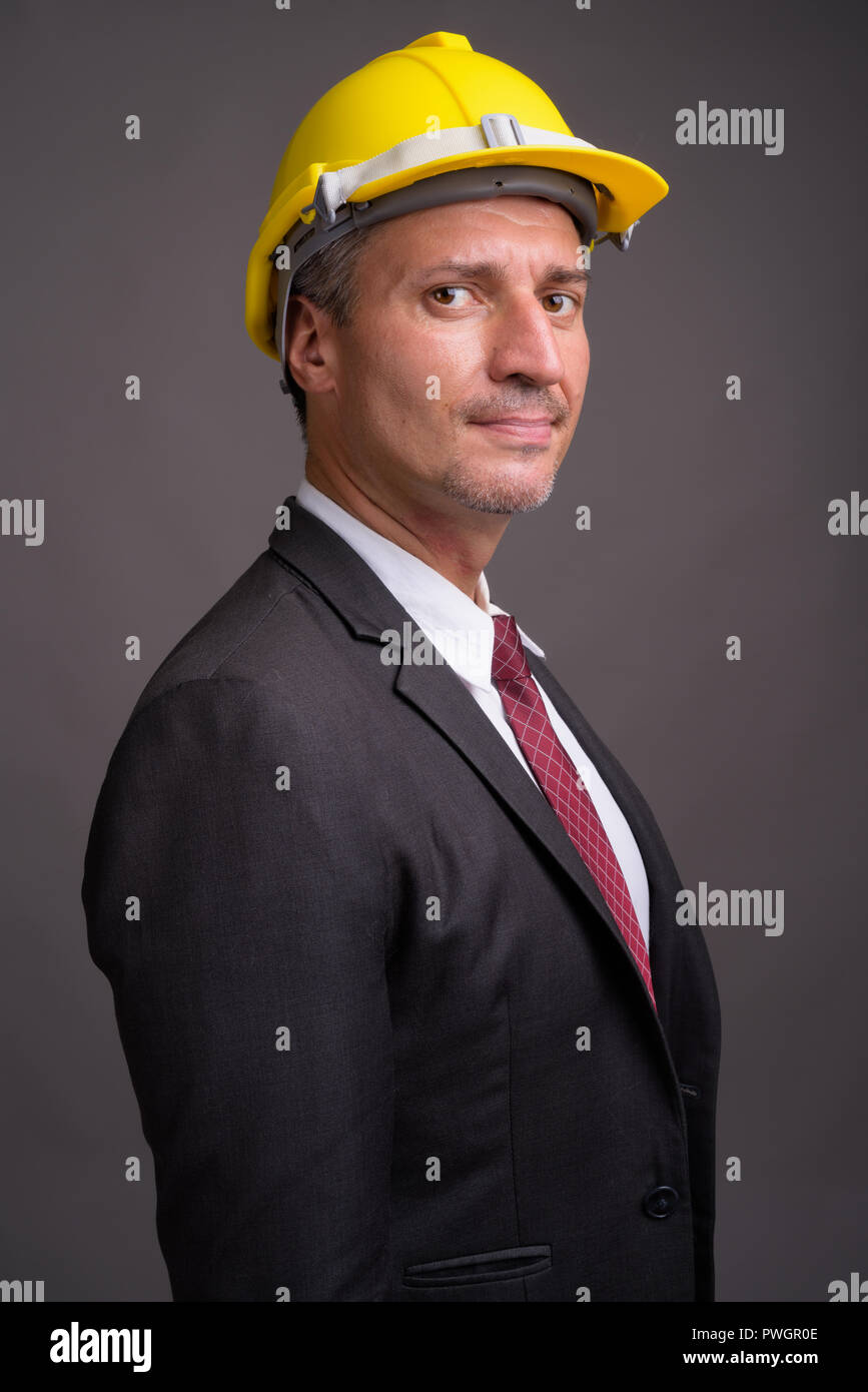 Portrait von Geschäftsmann mit hardhat gegen grauer Hintergrund Stockfoto