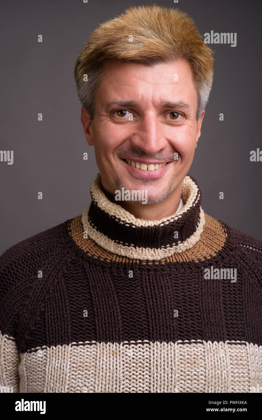 Mann mit blondem Haar zu tragen Rollkragen-pullover gegen Grau zurück Stockfoto