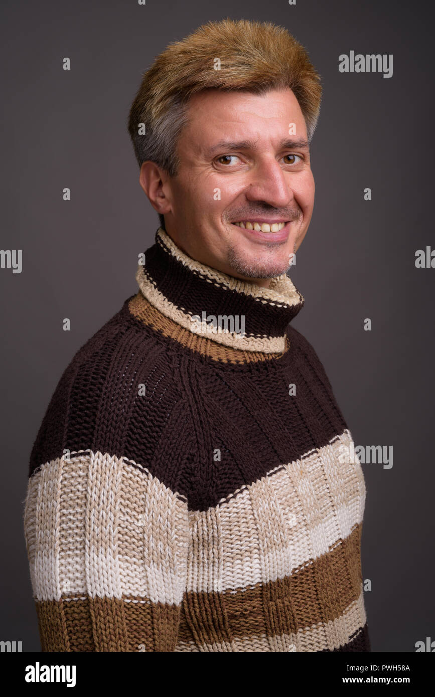 Mann mit blondem Haar zu tragen Rollkragen-pullover gegen Grau zurück Stockfoto