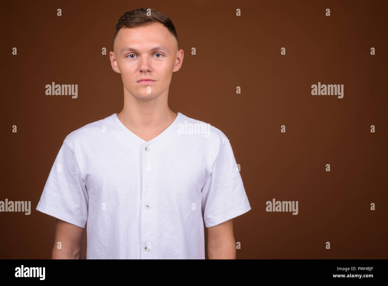 Junger Mann mit weißem Hemd gegen braunen Hintergrund Stockfoto