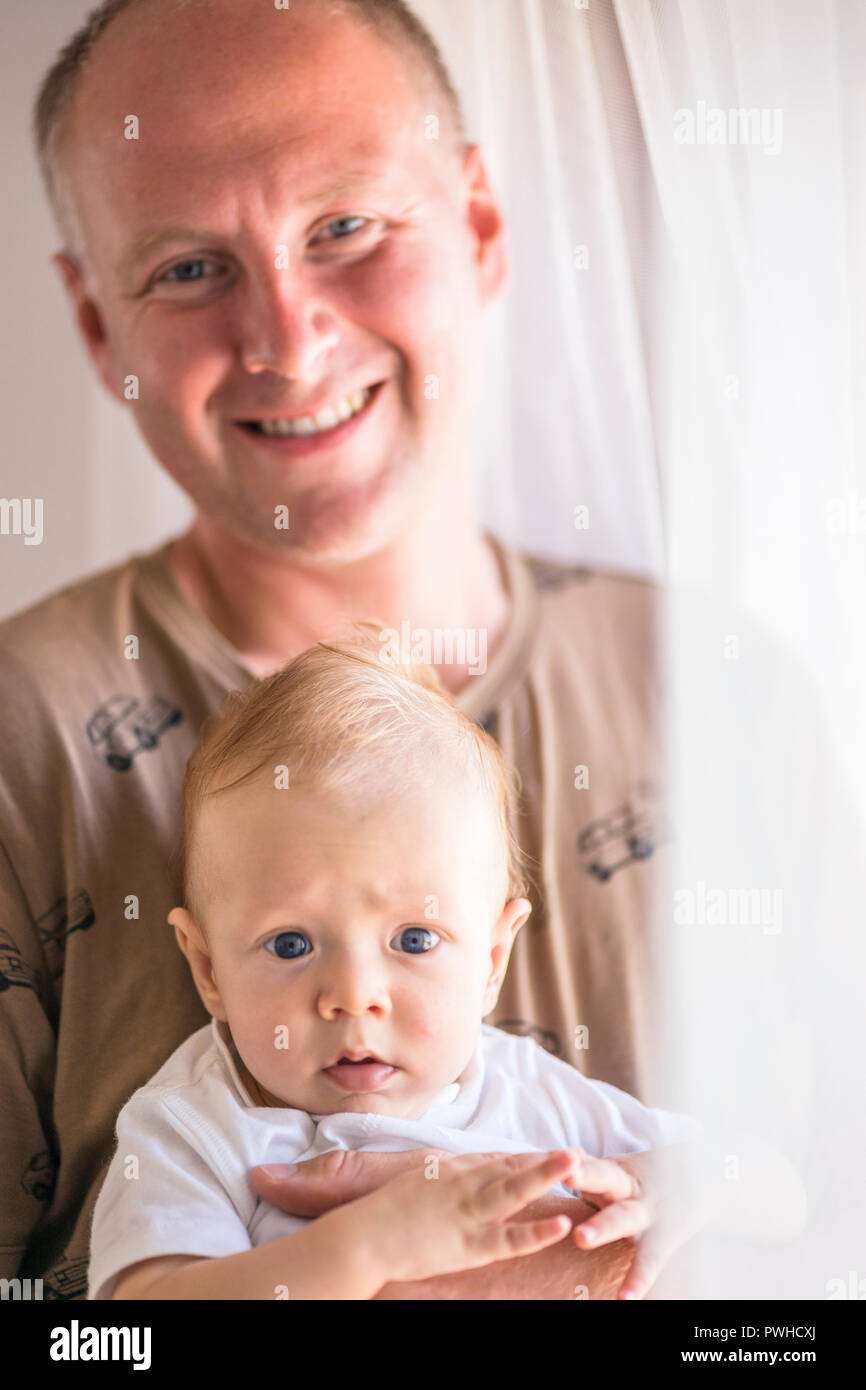 Lächelnd Vater hielt seinen schweren baby boy beide schauen in die Kamera Stockfoto