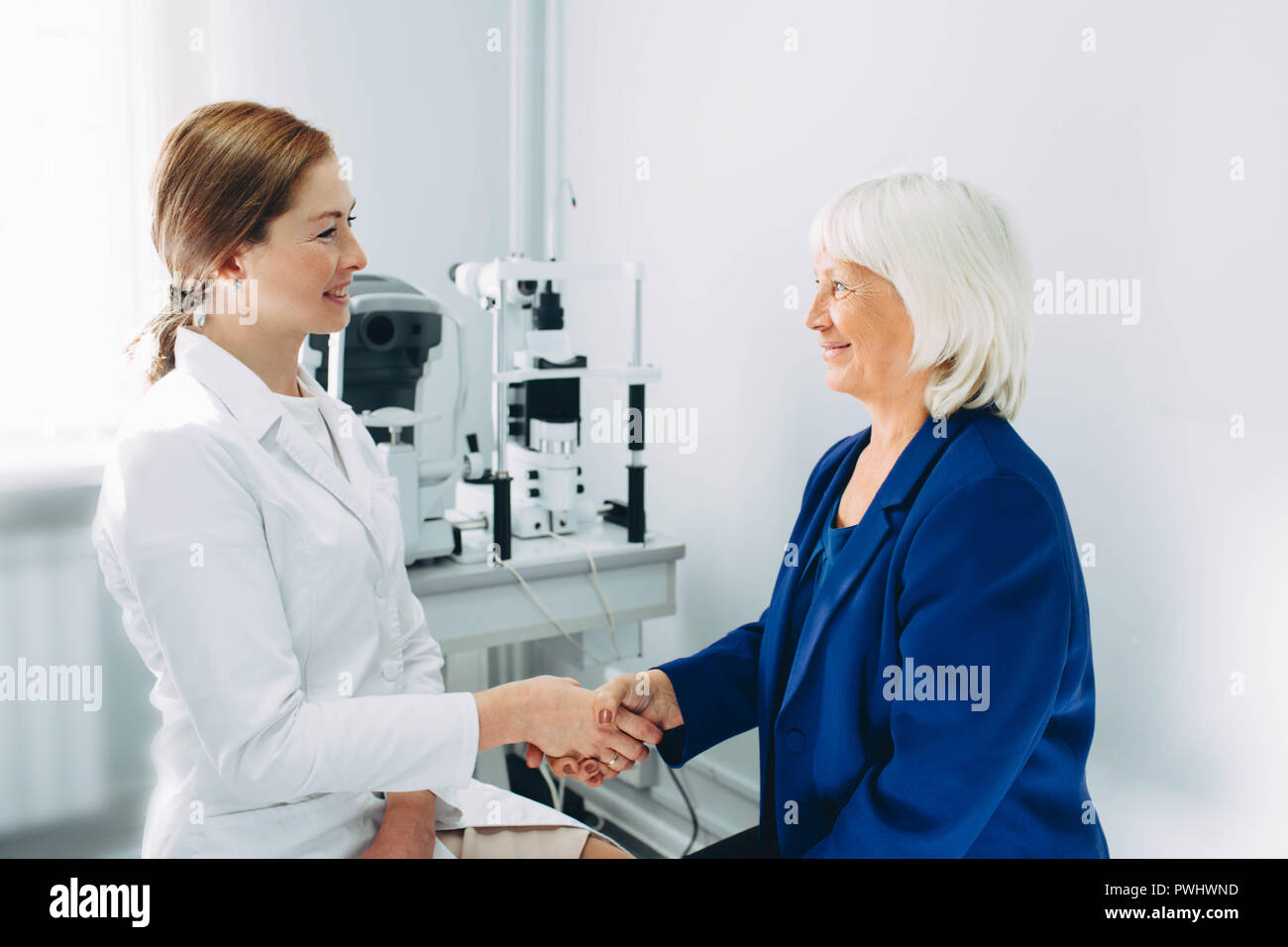 Handshake mit einem gealterten Patienten an optometrist Büro Stockfoto