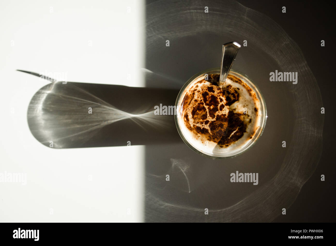 Ein Glas Milch Kaffee der gespiegelten Teil einer weißen Tisch projiziert Licht in einem runden Weg Stockfoto