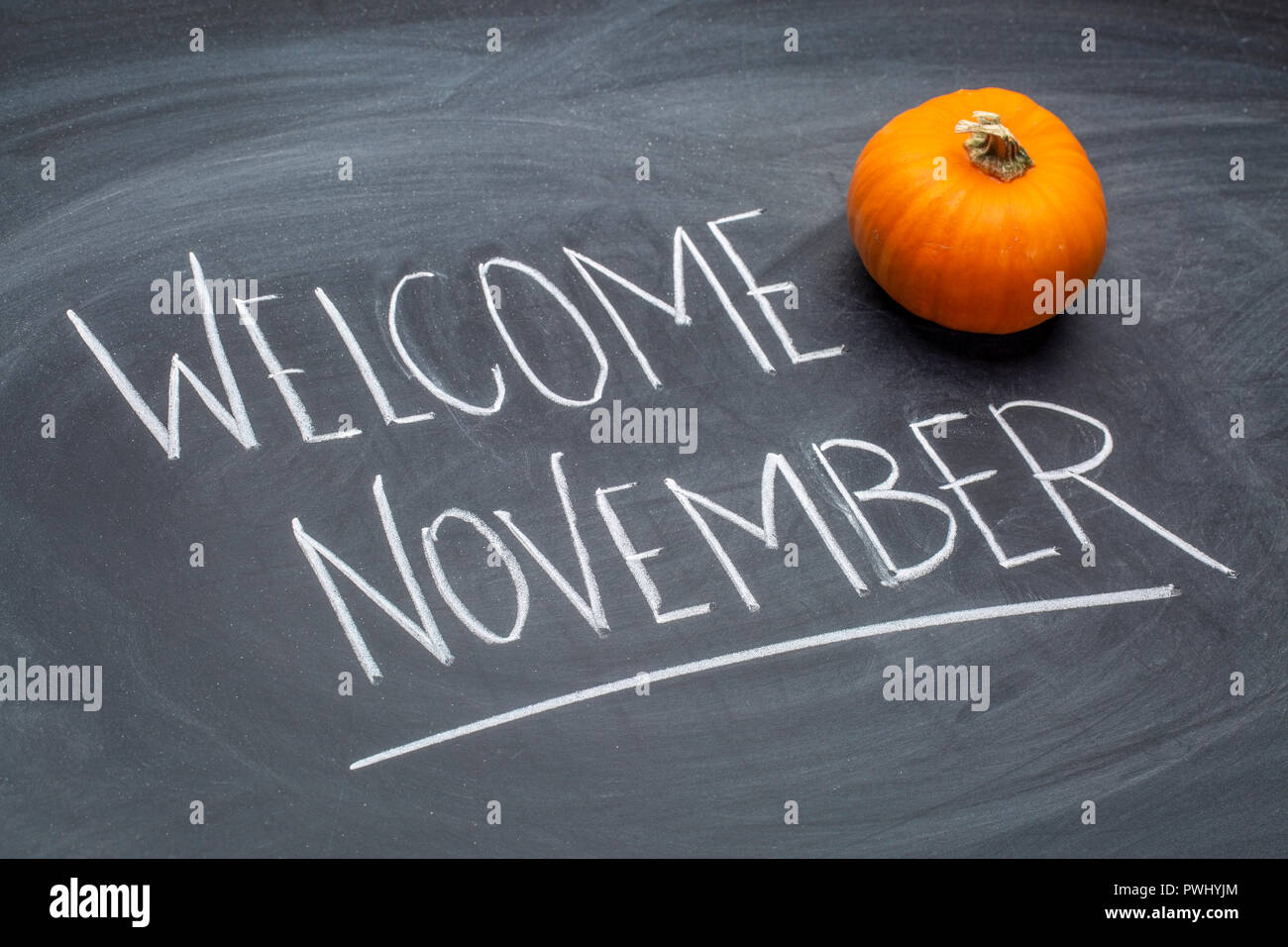 Willkommen November - weißer Kreide Handschrift auf einem Schiefer Tafel mit einem Kürbis Kürbis Stockfoto