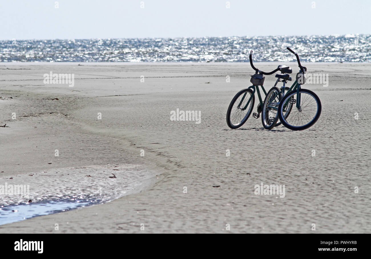 Zwei Fahrräder auf einem Meer Strand geparkt Stockfoto