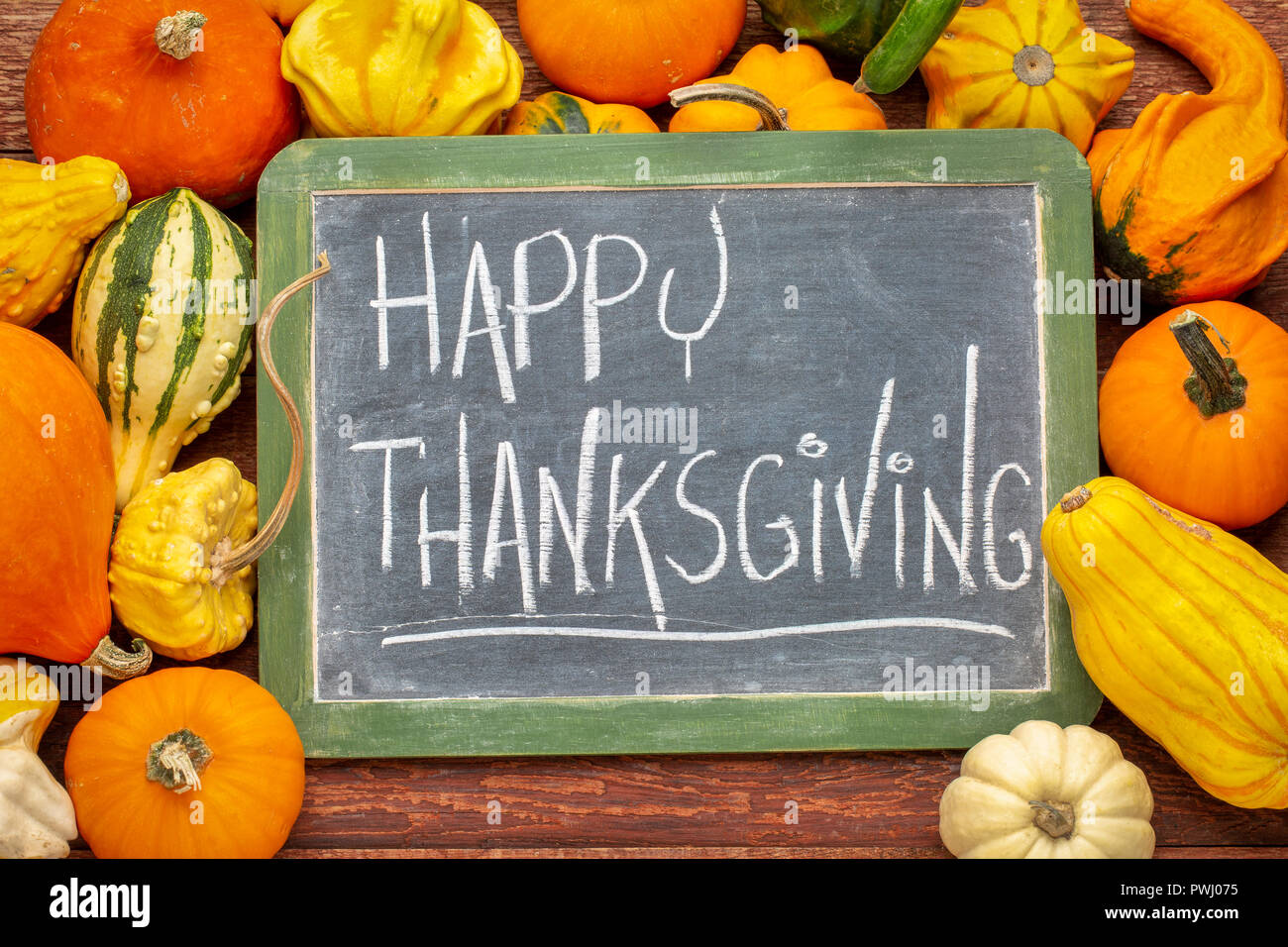 Happy Thanksgiving - weißer Kreide Handschrift auf einer Schiefertafel Schultafel im Winter Kürbis Kürbisse und Umgeben Stockfoto