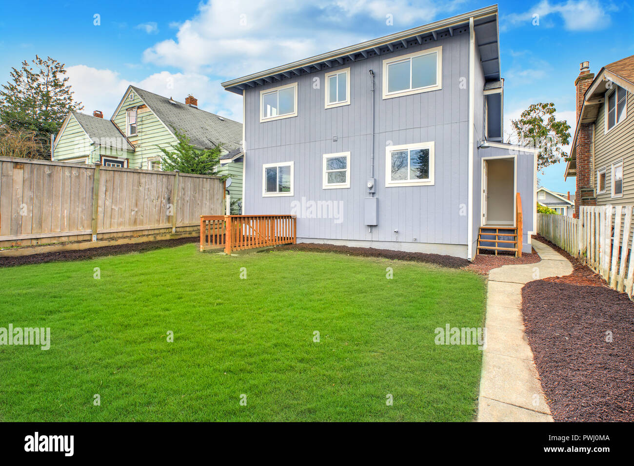 Blue Home Exterieur mit großen, vollständig eingezäunten Garten und gepflegten Rasen. Stockfoto
