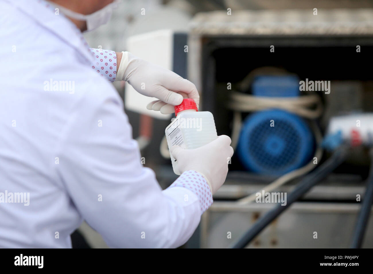 Details mit den Händen eines Arztes in der medizinischen Kleid mit einem Kunststoff Empfänger, um zu testen, ob das Wasser aus einem Tank trinkbar, Stockfoto