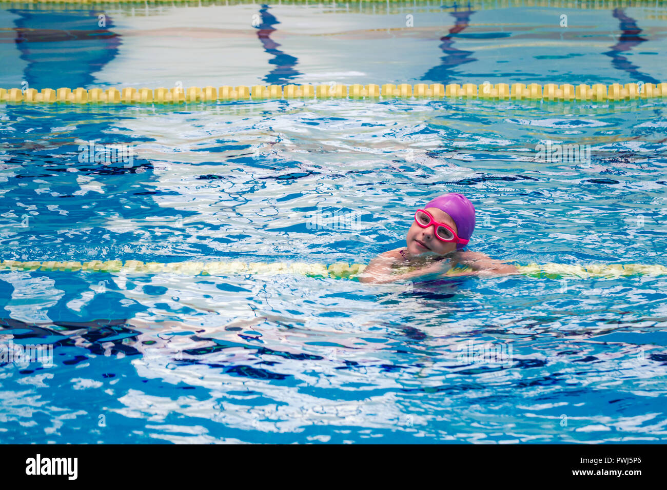 Süße kleine Mädchen mit lila Badeanzug Schwimmen im Pool Stockfoto