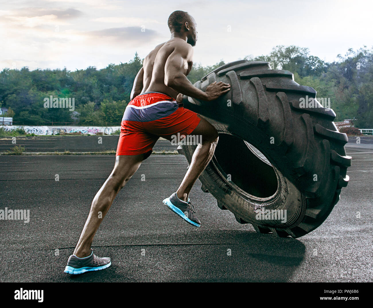 Schöne afrikanische amerikanische muskulösen Mann spiegeln große Reifen outdoor. Stockfoto