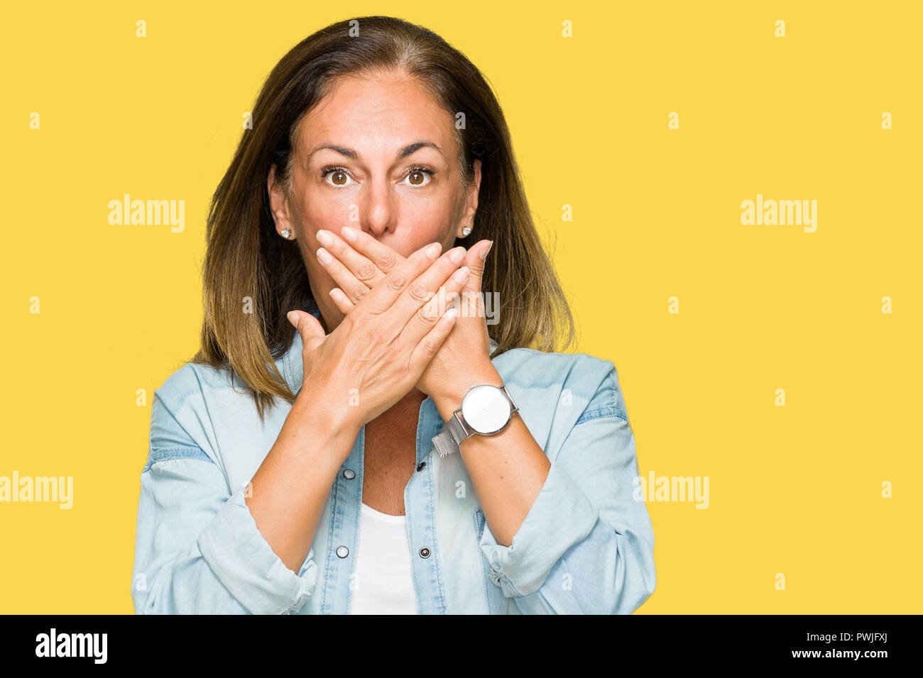Mittleres Alter erwachsene Frau legere denim Shirt über isolierte Hintergrund für Mund mit den Händen für den Fehler schockiert. Geheime Konzept. Stockfoto