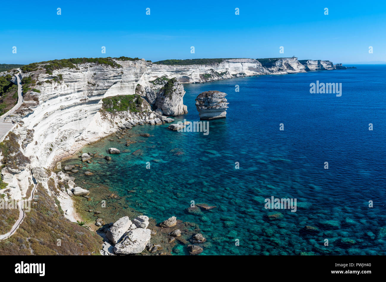 Panoramablick auf den Klippen von Bonifacio und die Grain de Sable im Süden von Korsika, mit Blick auf einen ruhigen blauen Meer unter blauem Himmel. Stockfoto