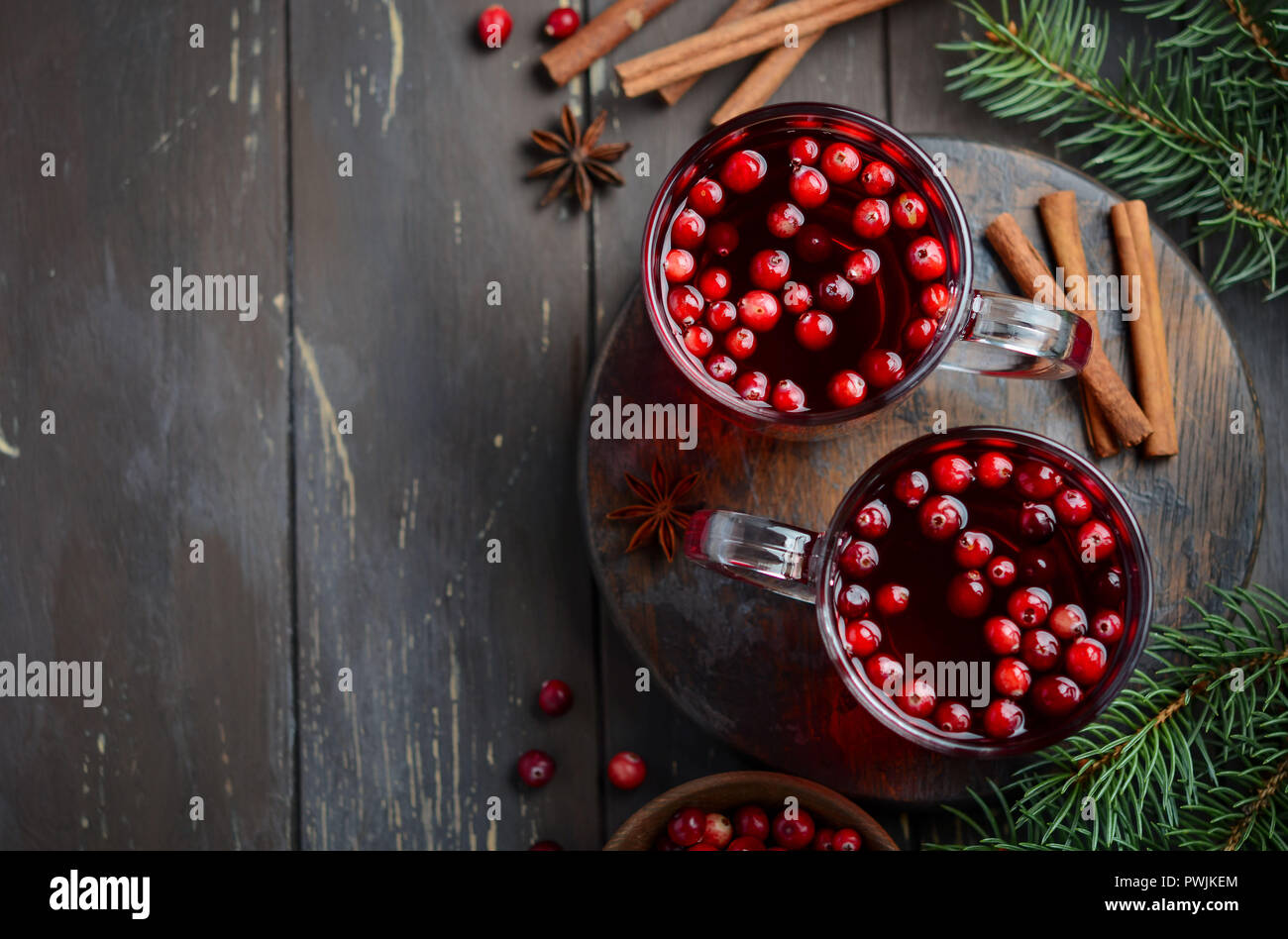 Cranberry Drink auf Holz- Hintergrund dekoriert mit Tannenzweigen, Gewürzen und frischen Beeren Stockfoto