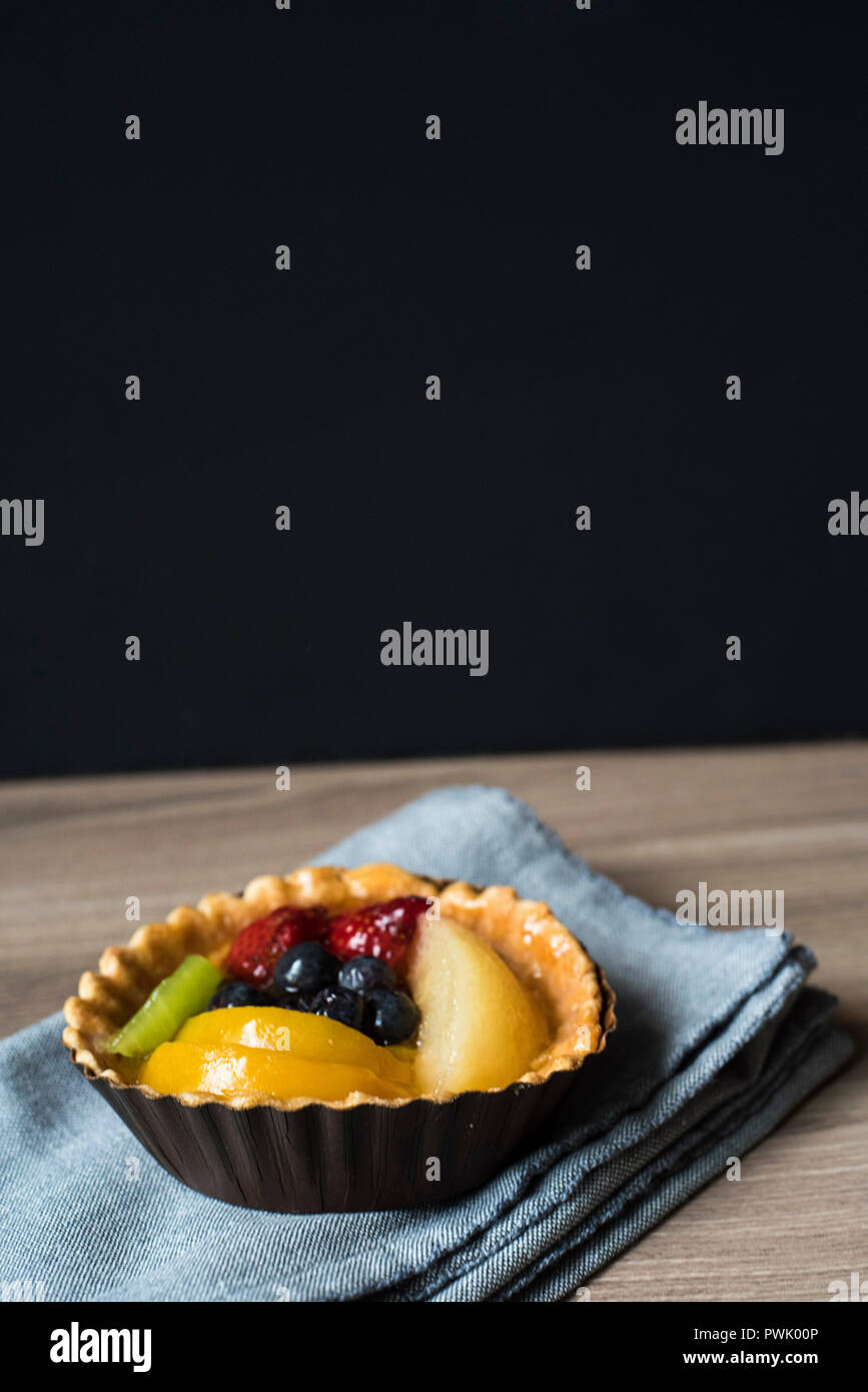 Frisches Obst Tartlette ruht in seiner Wrapper auf einem Tuch Serviette bereit zu Essen für ein Dessert oder Snack Stockfoto