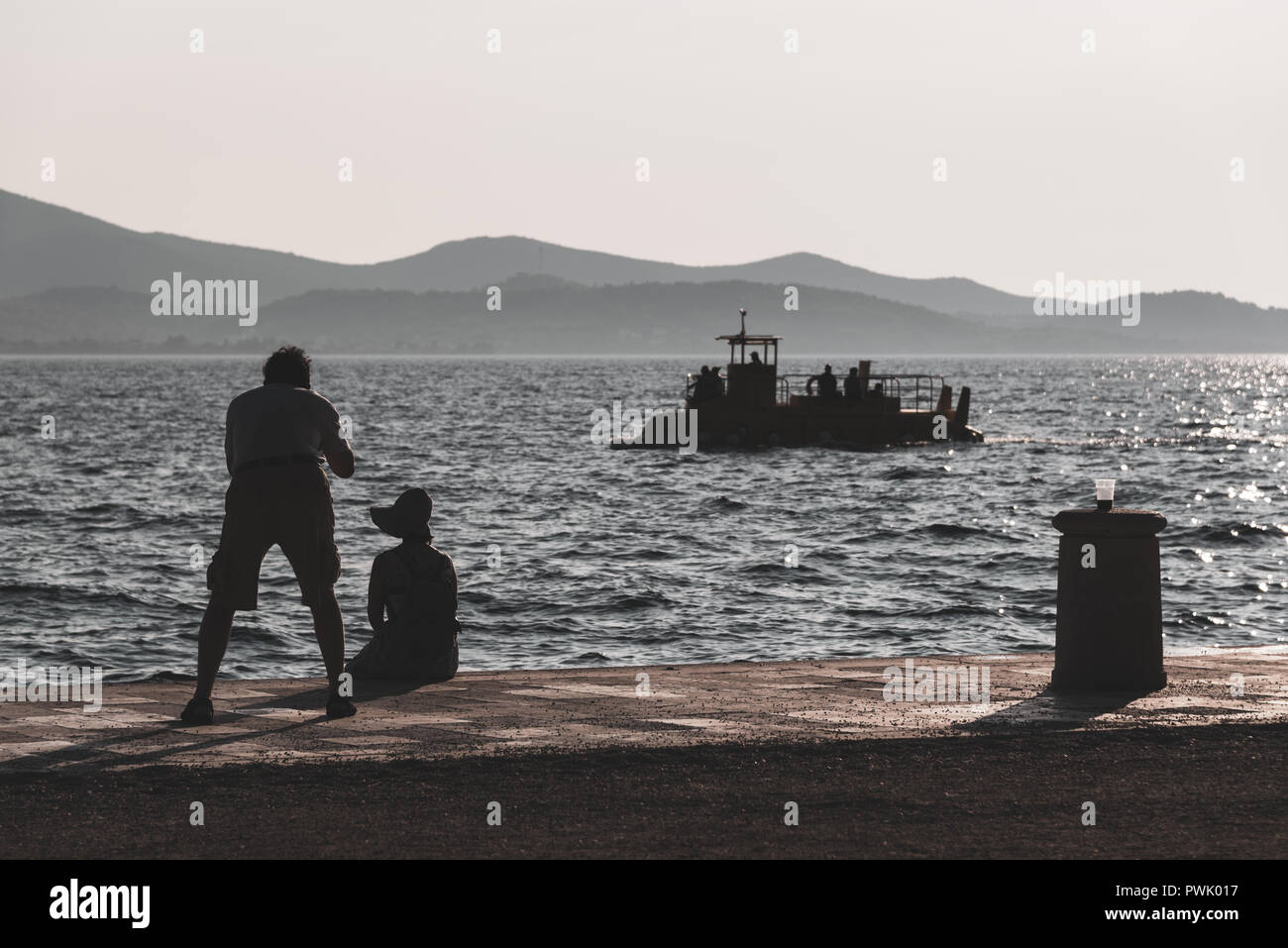 Paar silhouetted Touristen durch das Meer mit einer Kamera und in sanften Farbtönen gehalten. Stockfoto