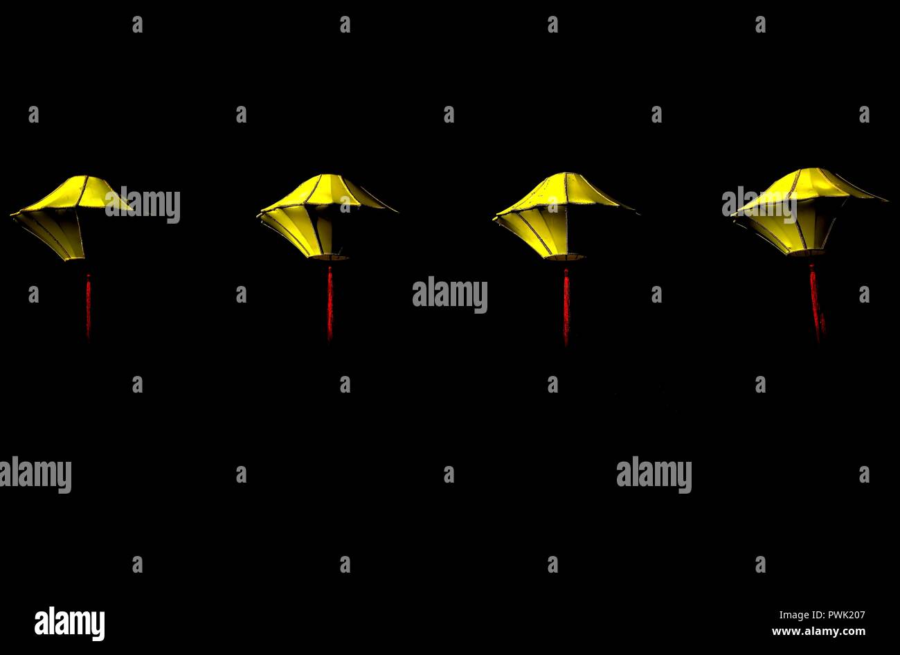 Reihe von vier hängenden gelben Seide Laternen vor einem dunklen Hintergrund mit Platz für Kopie isoliert Stockfoto