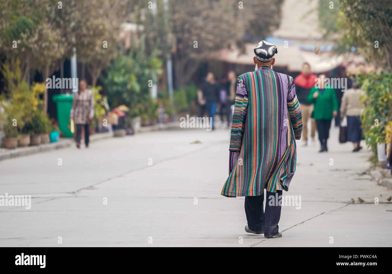 Kashgar, China Autonome Region Xinjiang Uygur. 16 Okt, 2018. Ein älterer Mann in Tracht gekleidet Spaziergänge auf einer Straße in Kashgar Stadt im Nordwesten Chinas Autonome Region Xinjiang Uygur, Okt. 16, 2018. Die antike Oasenstadt Kashgar, im westlichsten Teil von China in der Nähe der Grenze zu Kirgisistan, Tadschikistan, Afghanistan, Pakistan, war eine wichtige Zwischenstation auf der Seidenstraße und hat als lebendige Drehscheibe der Wirtschaft und verschiedenen Kulturen wiederbelebt worden. Credit: Hu Huhu/Xinhua/Alamy leben Nachrichten Stockfoto