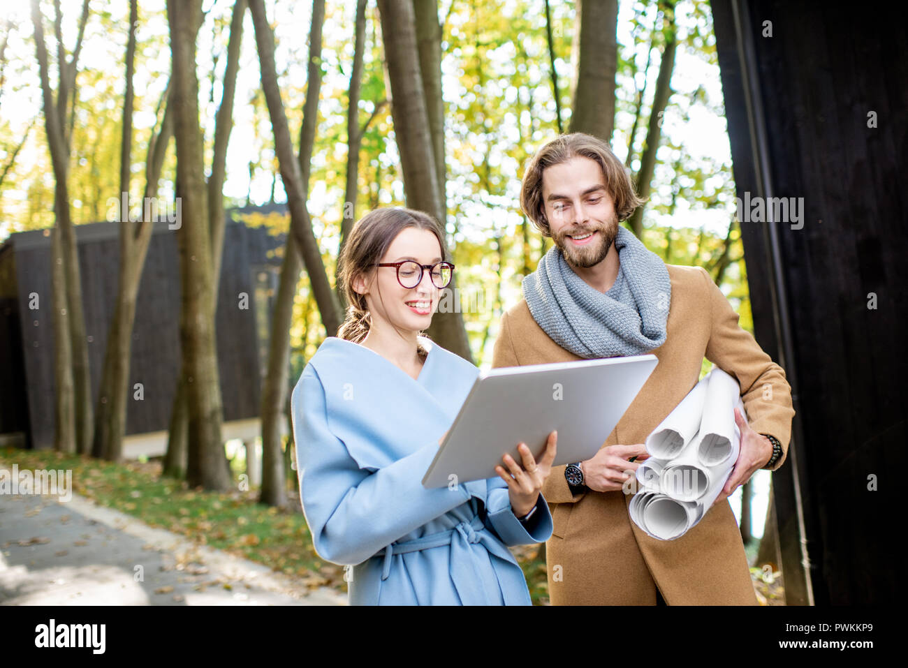 Kreative Paar der Architekten oder Designer arbeiten mit Laptop und Zeichnungen draußen im Wald Stockfoto