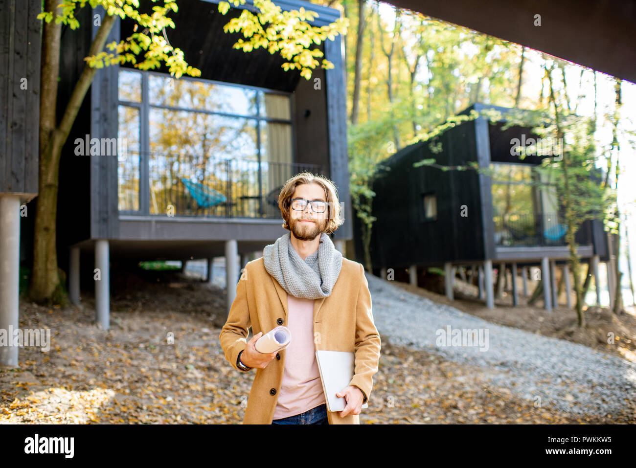 Porträt eines gutaussehenden Mann Architekt stehend mit Laptop vor der moderne Häuser im Wald Stockfoto