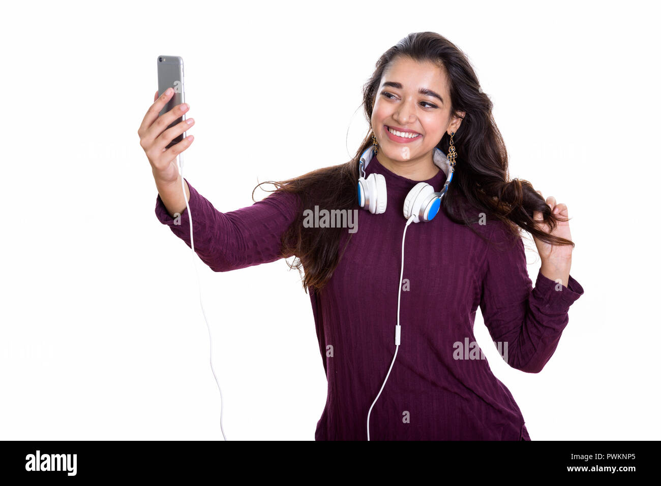 Junge indische Frau glücklich lächelnd, während Kopfhörer um tragen Stockfoto