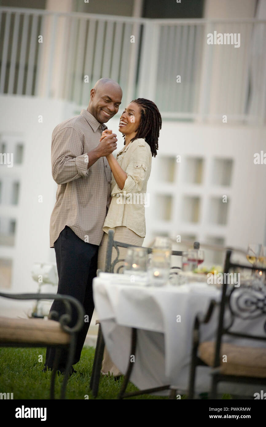 Lächelnd Mann und Frau tanzen zusammen neben einem Tisch im Freien. Stockfoto