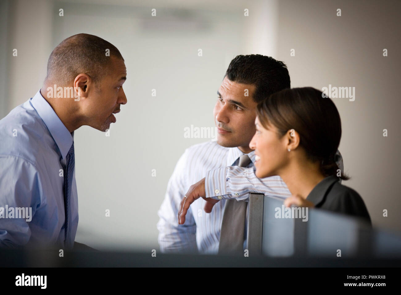 Mitte - Erwachsene Unternehmer im Gespräch mit zwei seiner Kollegen in einem Büro. Stockfoto
