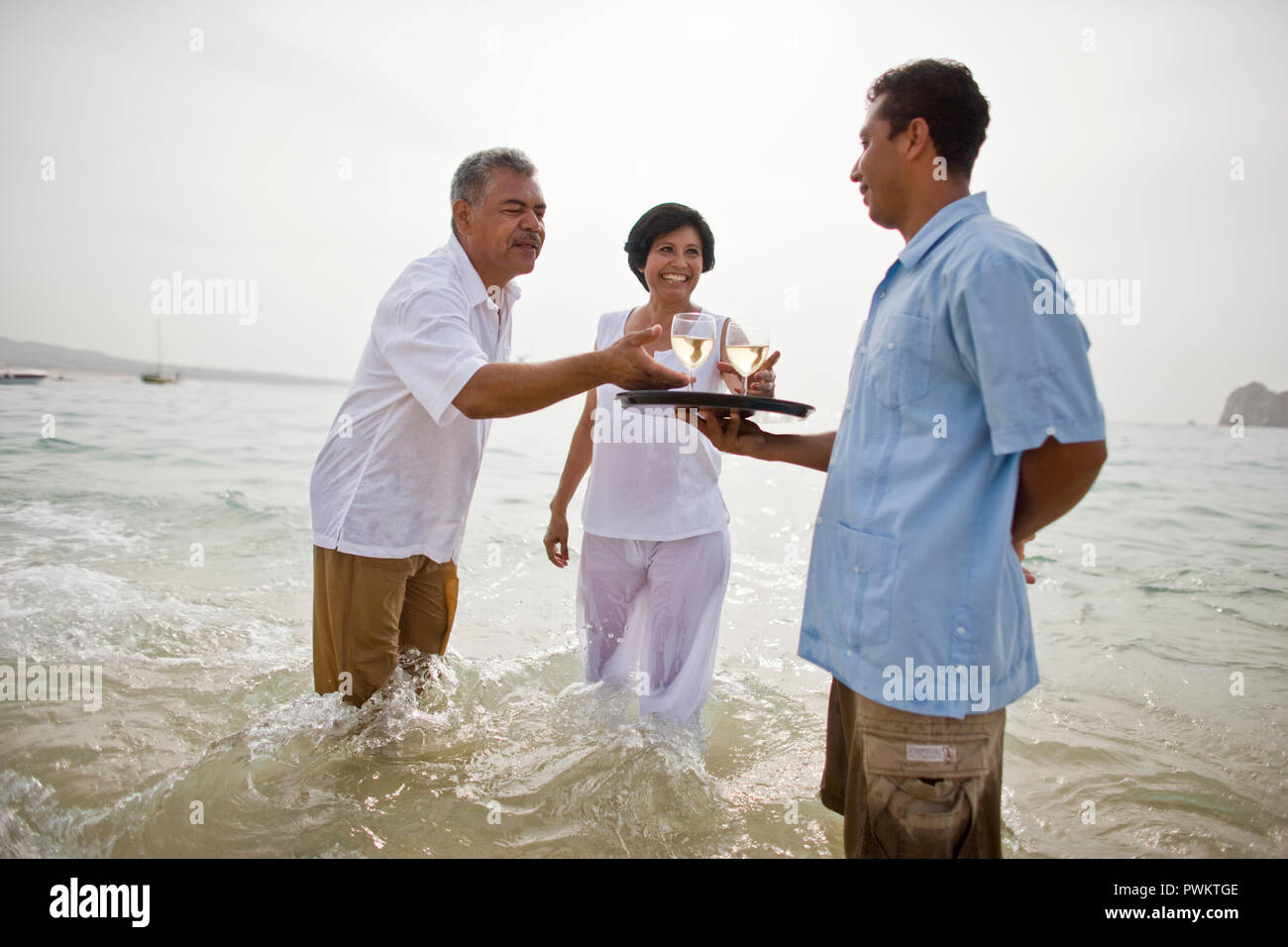 Kellner serviert Wein, reifes Paar im Ozean Stockfoto