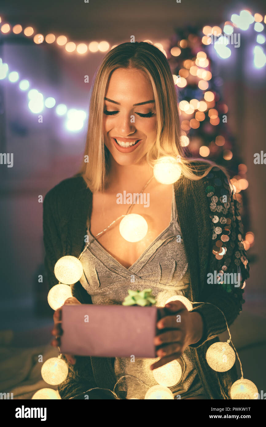 Süße junge lächelnde Frau mit Geschenk mit Weihnachten bubble Lights umgeben. Stockfoto