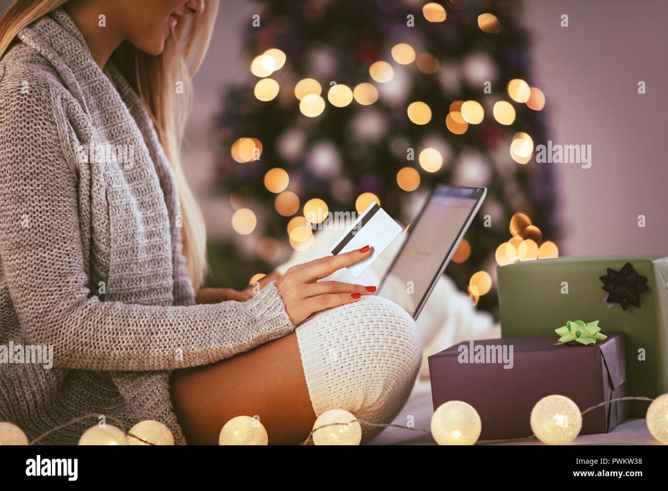 Glückliche junge Frau Entspannung zu Hause und online kaufen Weihnachtsgeschenke auf dem Laptop. Stockfoto